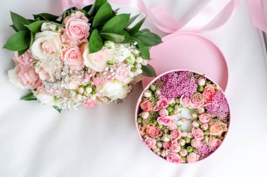 İçinde güller, çiçekler ve düğün buketi bulunan pembe yuvarlak kutuyu kapat. Gelinin nişan hediyesi olarak takılarla süslü romantik bir kompozisyon..