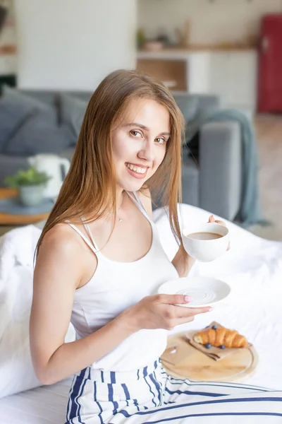 Joven Mujer Sonriente Sosteniendo Taza Café Cama Con Pijamas Acogedora —  Fotos de Stock