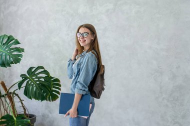 Kahverengi sırt çantası ve kitaplarla gülümseyen beyaz kız.