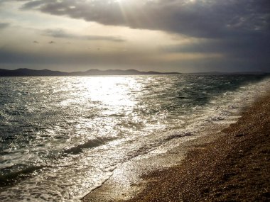 Deniz dalgaları ile güzel bir gün batımı sırasında bir çakıl plaj