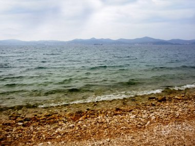 Bulutlu bir gün ve çakıl bir plajda grev ler bir haddeleme deniz.