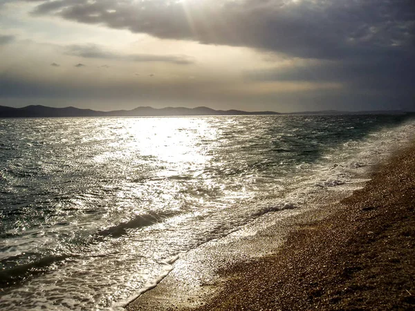 Deniz dalgaları ile güzel bir gün batımı sırasında bir çakıl plaj