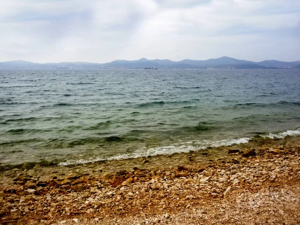 Bulutlu bir gün ve çakıl bir plajda grev ler bir haddeleme deniz.