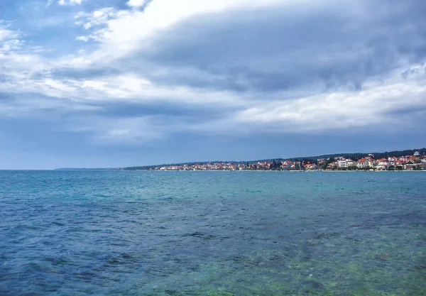 Bulutlu bir günde bir kasaba içinde belgili tanımlık geçmiş ile dalgalar küçük deniz.