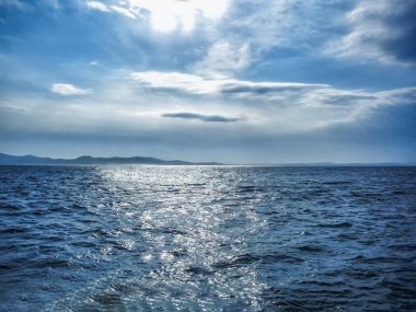 Bir bulutlu gün boyunca dalgalı denizde günbatımı.