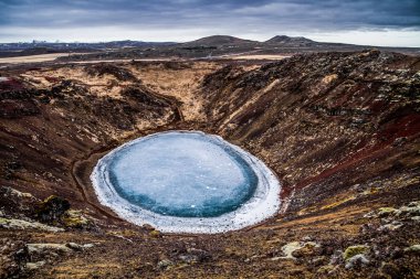 Kerid volkanik krater ve onun mavi su birikintisi, Golden Circle, İzlanda. Kış renkleri güzel Kerio veya Kerid Batı İzlanda'krater. Kırmızı volkanik kaya, yeşil yosunlu yamaçları ve turkuaz Gölü buz kırma bir daire.