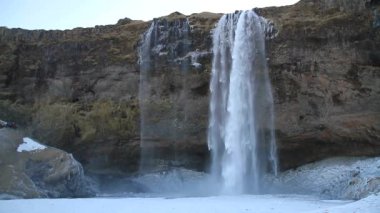 Kış aylarında İzlanda'daki güzel Seljalandsfoss. Kışın, nehir yansıma güzel şelale Seljalandsfoss gündoğumu ışıklar altında donmuş. Seljalandsfoss İzlanda'daki Güney bölgesinde yer alan.