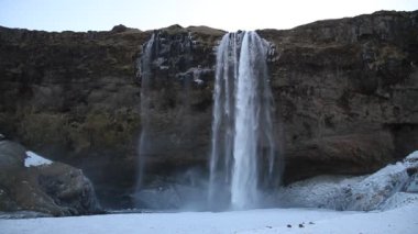 Kış aylarında İzlanda'daki güzel Seljalandsfoss. Kışın, nehir yansıma güzel şelale Seljalandsfoss gündoğumu ışıklar altında donmuş. Seljalandsfoss İzlanda'daki Güney bölgesinde yer alan.