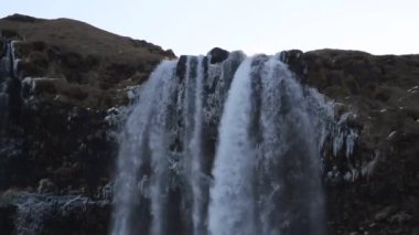 Kış aylarında İzlanda'daki güzel Seljalandsfoss. Kışın, nehir yansıma güzel şelale Seljalandsfoss gündoğumu ışıklar altında donmuş. Seljalandsfoss İzlanda'daki Güney bölgesinde yer alan.