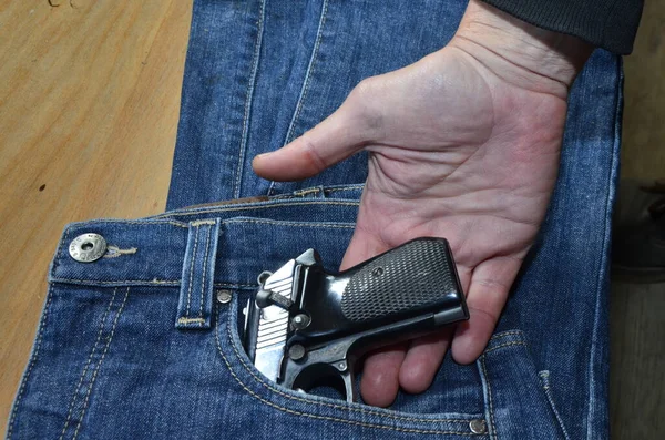 Gun in a pocket of jeans trousers fighting loaded.Pistol in the pocket of jeans.