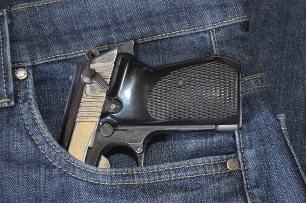 Gun in a pocket of jeans trousers fighting loaded.Pistol in the pocket of jeans.