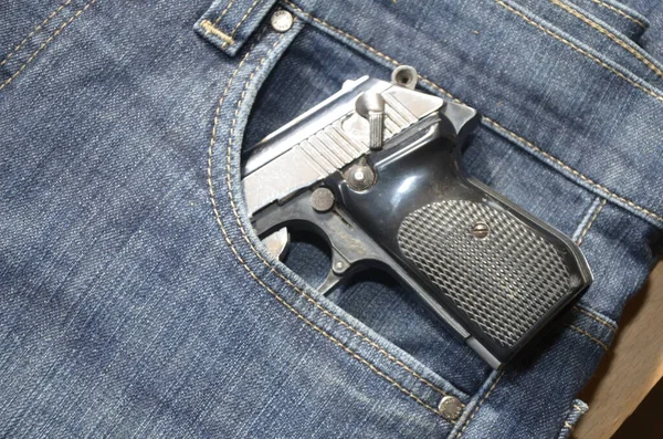 Gun in a pocket of jeans trousers fighting loaded.Pistol in the pocket of jeans.