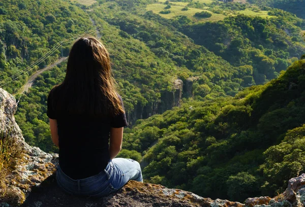 aşağı bakıyor bir uçurumun kıyısında oturan genç