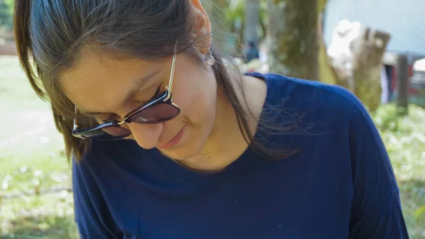 Kız gözlüklü, çömelmiş gülümseyen bir ormanda