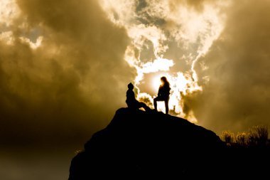 epik bir gökyüzü ile bir dağın tepesinde siluetleri