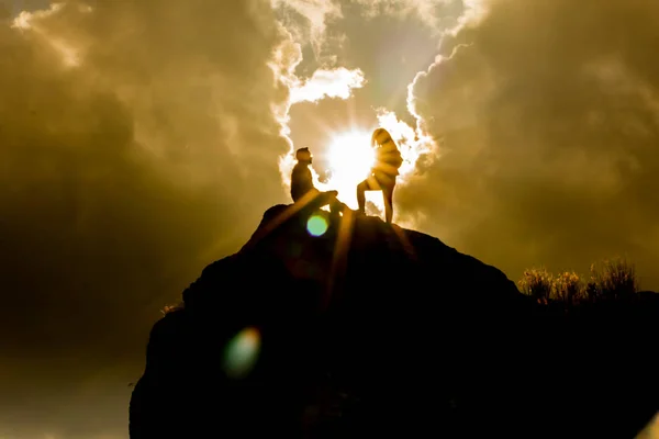 epik bir gökyüzü ile bir dağın tepesinde siluetleri