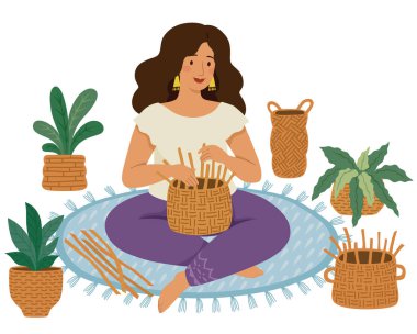 Yerde el yapımı hasır sepetler ve bitkilerle çevrili DIY sepetleri ören kadın.
