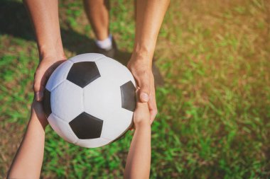 Onun küçük ile Yakışıklı baba eğleniyor ve yeşil çimenlik çim üzerinde futbol oynuyor