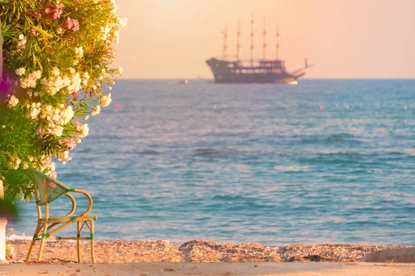 美丽的场景与游船帆船航行在海上日落在地平线上 从前景椅子的海滩上看风景 — 图库照片