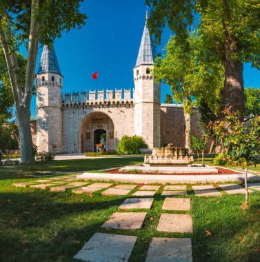 Topkapı Sarayı gate kuleleri ve duvar, Istanbul, Türkiye. Yeşil çim ve ağaçların ön planda Park. Arka plan mavi gökyüzünde.