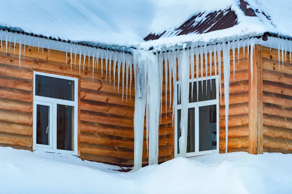 Maison en bois couverte de neige et de glaçons — Photo