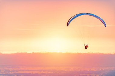 Günbatımında Almanya, Bavyera, Avrupa 'da paraglider. Arkaplanda bulutlar olan turuncu gökyüzü.