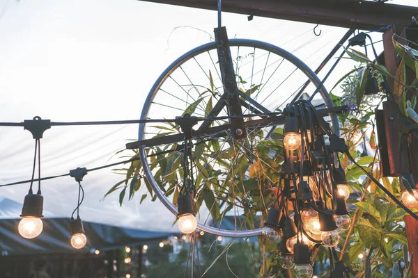 Vintage minimal light bulbs hanging with garden decorative wheel, color filter applied for soft vintage look