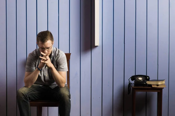 Стресовий Чоловік Сидить Кімнаті Синьою Пастельною Стіною — стокове фото
