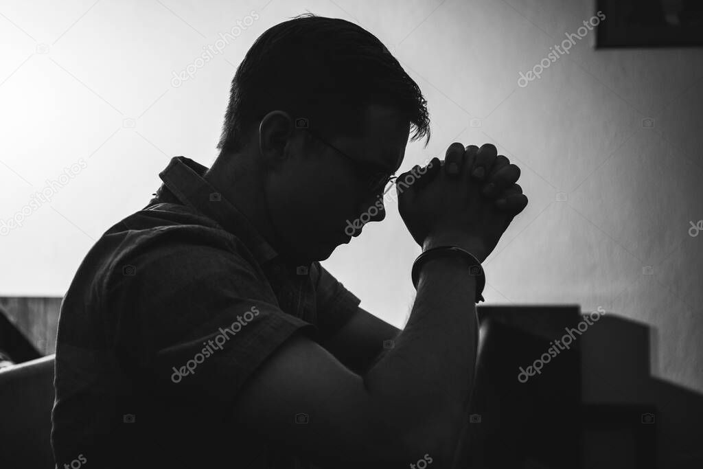 Silhouette of man praying in church in monotone