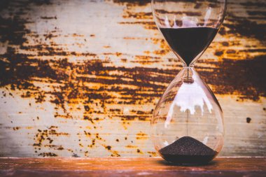 Cam saat, paslı arka planda siyah kum damlıyor.