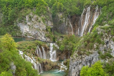 Hırvatistan ulusal park şelalesi, şelalenin üzerinde yürüyen turistlerle dolu.