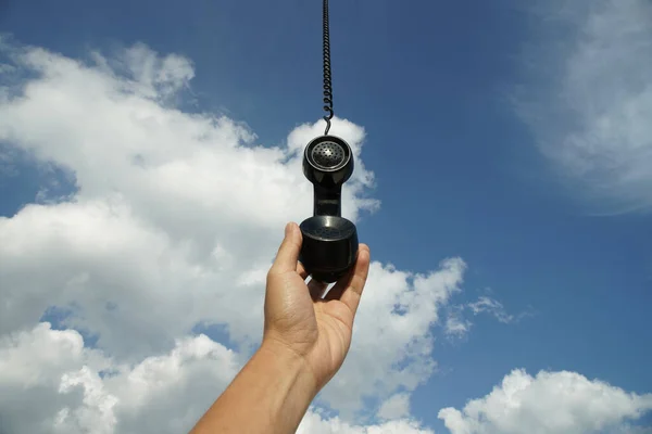 Gökyüzünden sarkan eski siyah bir telefon. Kavramsal fotoğrafçılık yukarıdan biriyle konuşuyor.
