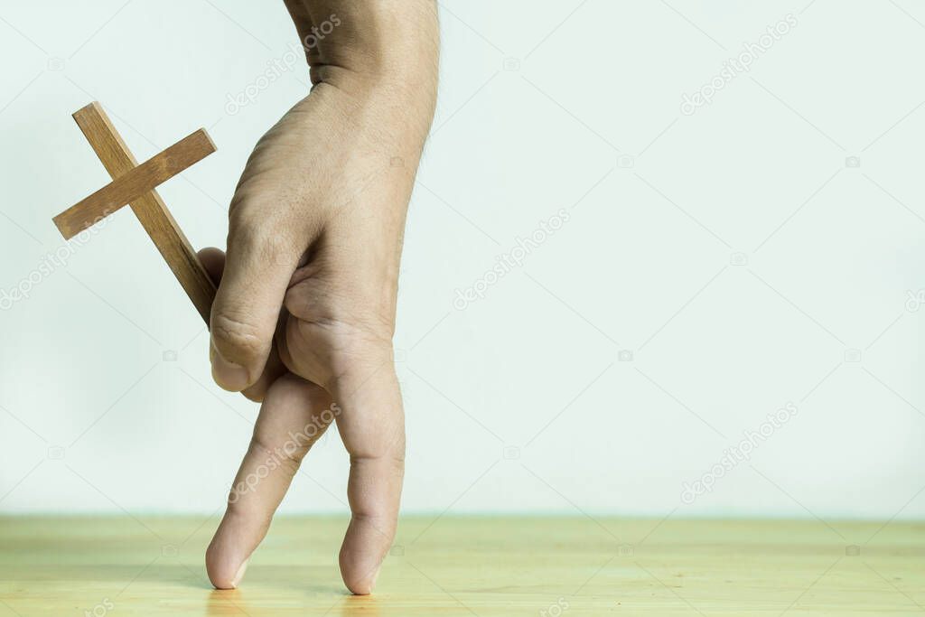 Hand holding wooden cross with finger in walking gesture