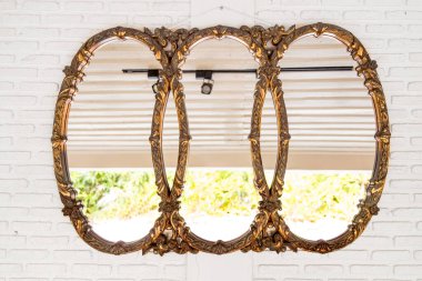 Beyaz tuğlalı duvarda klasik altın çerçeve ayna yansıtan tavan ve yüksek anahtar parlak yapraklar