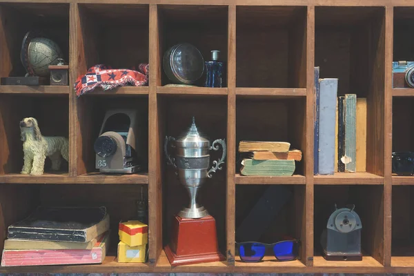 Vintage shelf with books, trophy, sunglasses, old camera, and other retro things. Decorating props oldie style wall