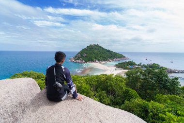 Kayalıklarda oturmuş Nangyuan Adası, Koh Tao, Tayland manzarasını izleyen bir turist.