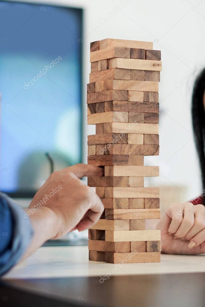 Hands playing jenga wooden tower game