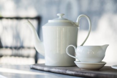 Beyaz çay demliği ve fincanı granit masaya koyun.