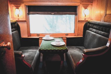 Travelling inside a luxurious vintage train carriage, private room with window view. Tea set served on table clipart