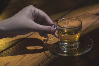 Bir fincan çayı elinde tutan kadın dramatik bir şekilde sert ışık altında.