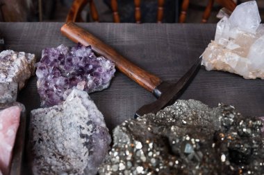Raw gems stones on table with hammer in miner's shop clipart