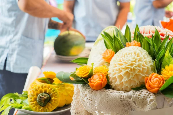 Fruit carving art, in preparation process with blurry artist in the background