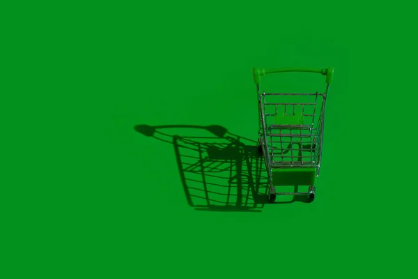 Green Shopping Trolley Green Background Harsh Shadow Caston Floor — Stock Photo, Image