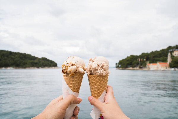 Hand holding ice cream cones with sea background