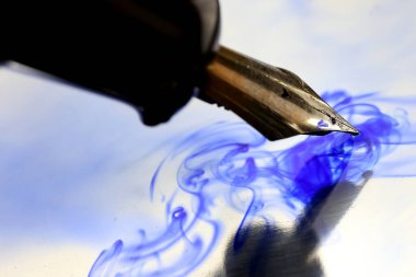 Su ve mavi mürekkebe eski tip kalem batırma.