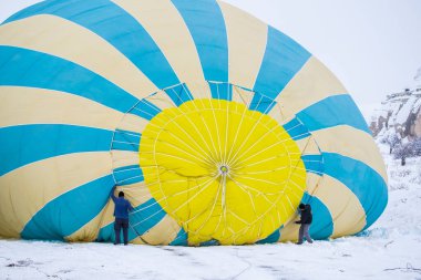 İşçiler kar tarlasında dev sıcak balonları hazırlıyorlar.