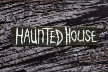 Haunted house sign on gray dried wood texture background clipart