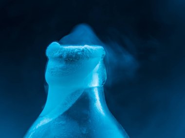 Iced chilled bottle mouth with ice vapor in dark background clipart