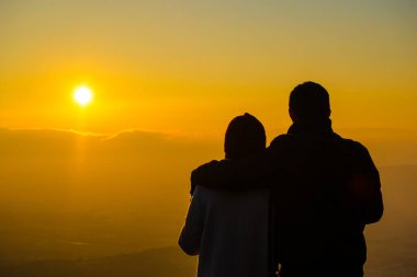 Güneşin doğuşunu izleyen çiftlerin silueti
