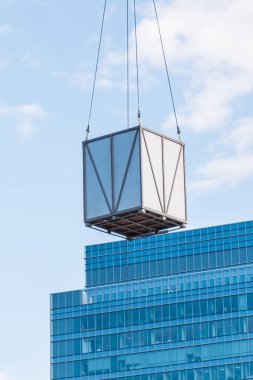 Nakliye konsepti. İnşaat alanında vinç kaldırılarak kaldırılan kutulu palet